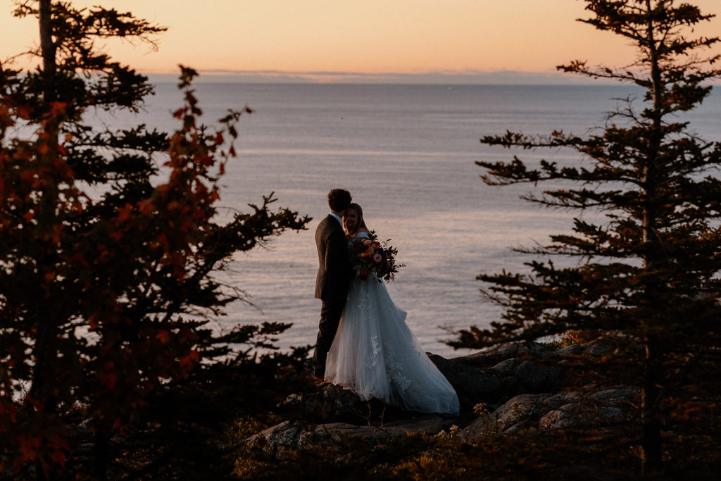 couple standing on the rocky coast sunrise